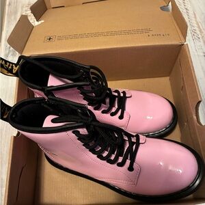 This is a pair of Dr. Martens Junior 1460 patent leather boots in pale pink.